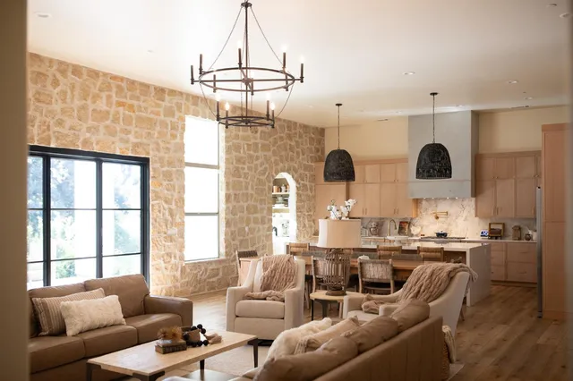a living room with stainless steel appliances granite countertop furniture a fireplace and a chandelier