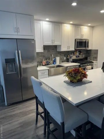a kitchen with stainless steel appliances a table chairs microwave and refrigerator