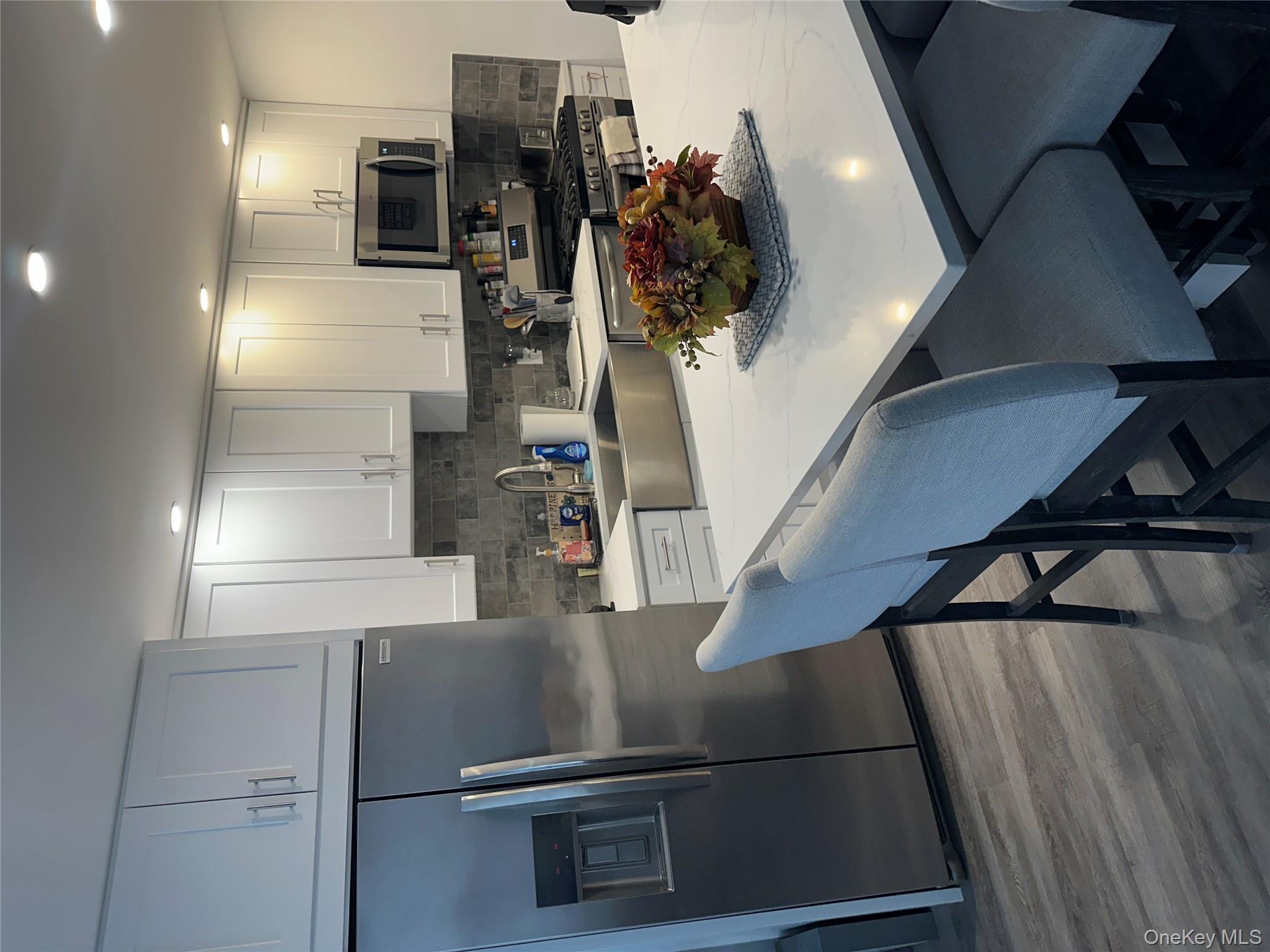 241-20 Northern Boulevard, Unit 1M Queens, NY 11362 - Photo 8 of 31 a kitchen with stainless steel appliances a table chairs microwave and refrigerator