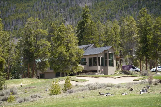 a front view of a house with a yard covered with snow and trees