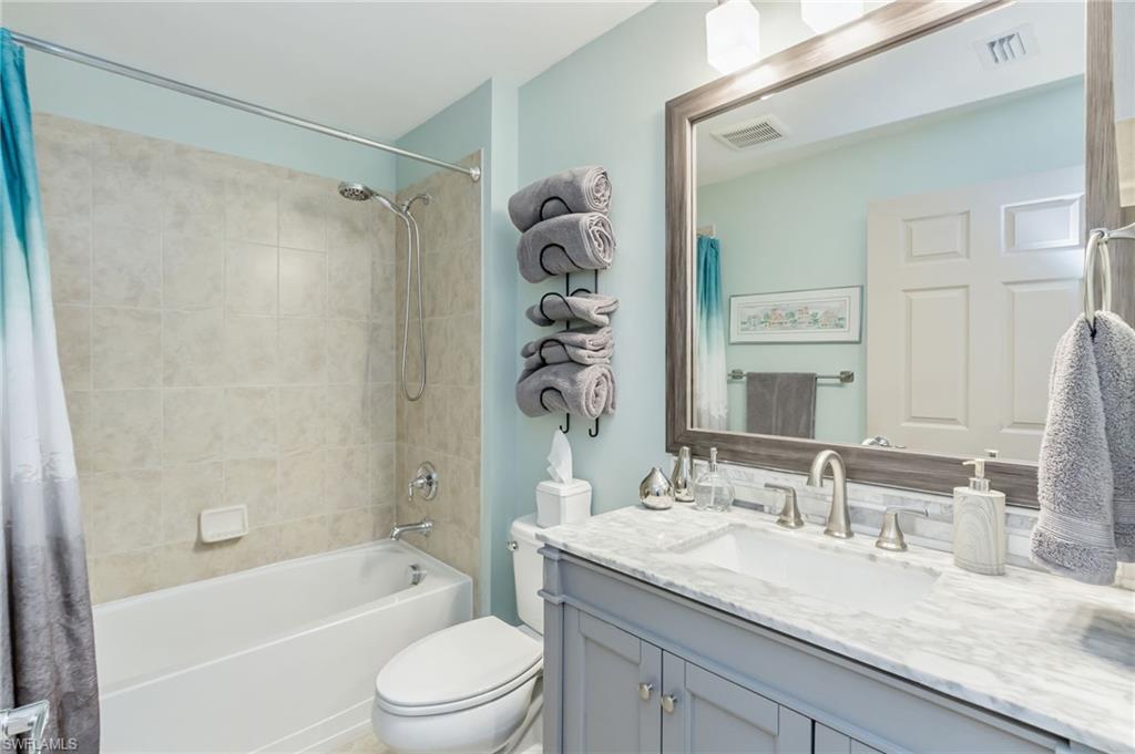 5801 Declaration Court Ave Maria, FL 34142 - Photo 20 of 38 a bathroom with a granite countertop sink a mirror a bathtub and a shower