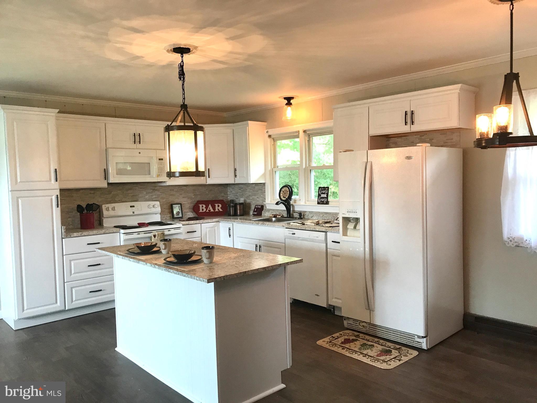 9671 Clarkes Road Bealeton, VA 22712 - Photo 3 of 12 a kitchen with refrigerator a stove a sink and white cabinets with wooden floor