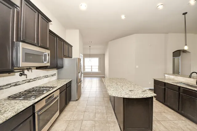 a kitchen with stainless steel appliances granite countertop a sink stove and refrigerator
