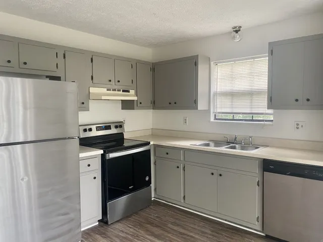 a kitchen with a sink a refrigerator a window and cabinets