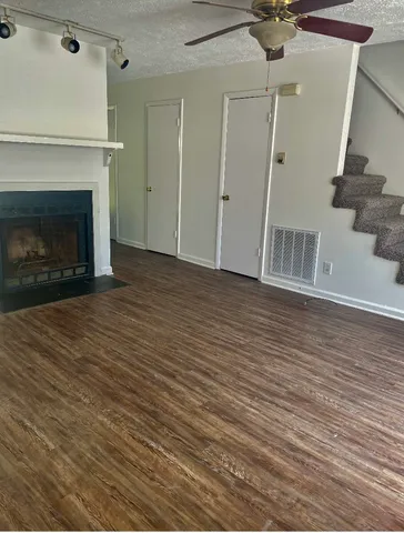 a view of an empty room with wooden floor fireplace and a window