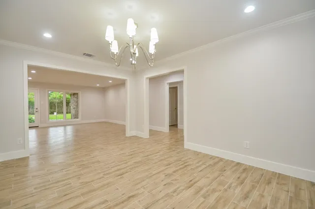 a view of an empty room with wooden floor and a chandelier