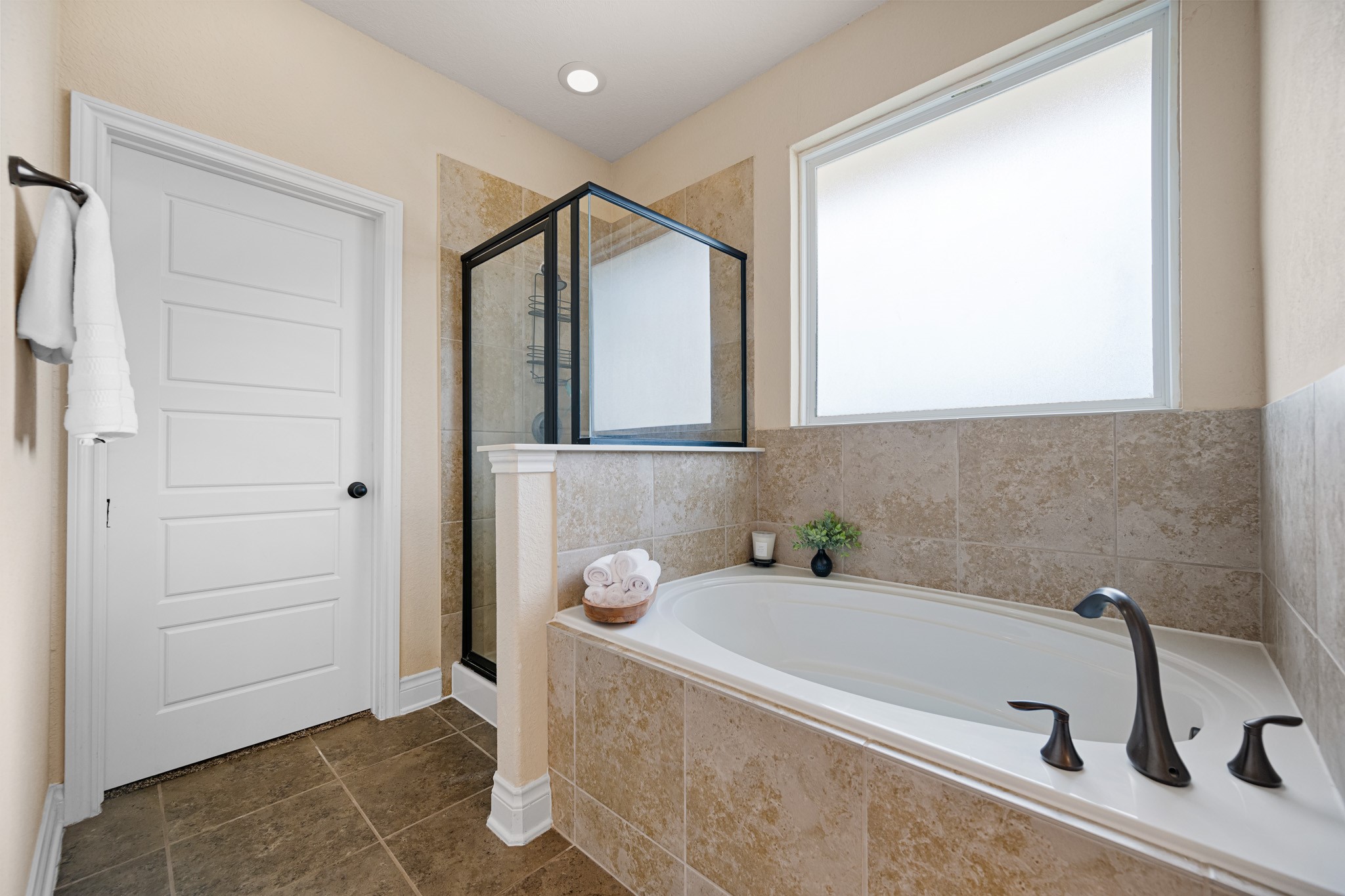 8131 Brinkmeyer Road Needville, TX 77461 - Photo 24 of 34 This bathroom features a spacious bathtub with modern fixtures, a glass-enclosed shower, and a large frosted window for natural light.