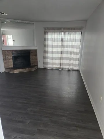 a view of empty room with wooden floor and fireplace