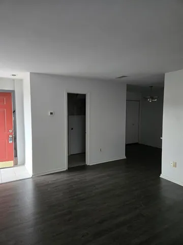 a view of an empty room with wooden floor and closet
