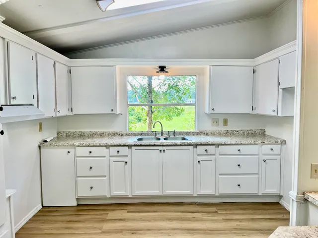 a kitchen with granite countertop white cabinets and a window
