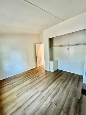 a view of an empty room with wooden floor and a ceiling fan
