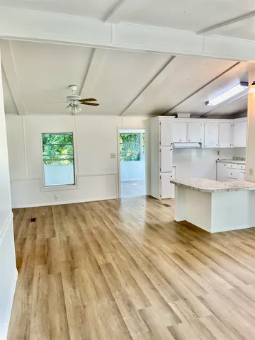 a view of kitchen and empty room with wooden floor