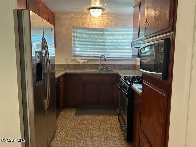 a kitchen with stainless steel appliances granite countertop a refrigerator a sink and a stove