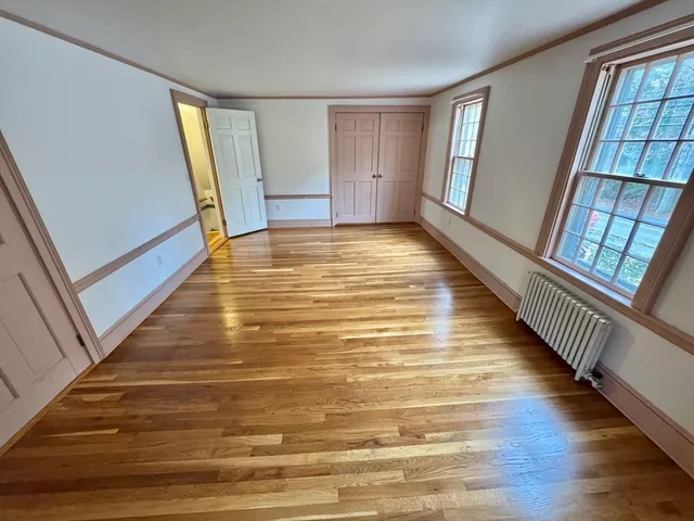 a view of an empty room with wooden floor and furniture