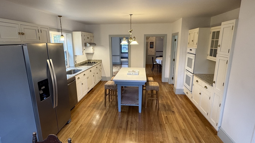 191 Chestnut Street, Unit 1 Duxbury, MA 02332 - Photo 2 of 20 a kitchen with stainless steel appliances a refrigerator a stove a dining table and chairs with wooden floor