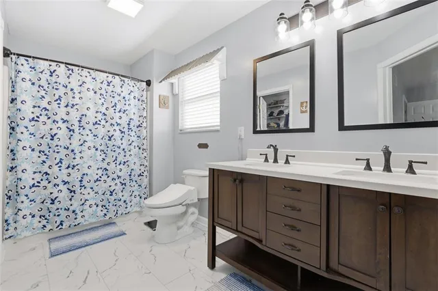 a bathroom with a double vanity sink toilet and a mirror