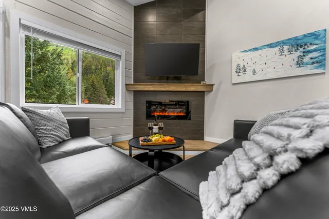 a living room with stainless steel appliances furniture wooden floor and kitchen view