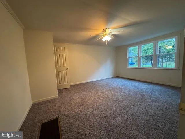 an empty room with windows and fan