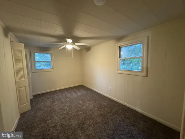 an empty room with windows and fan