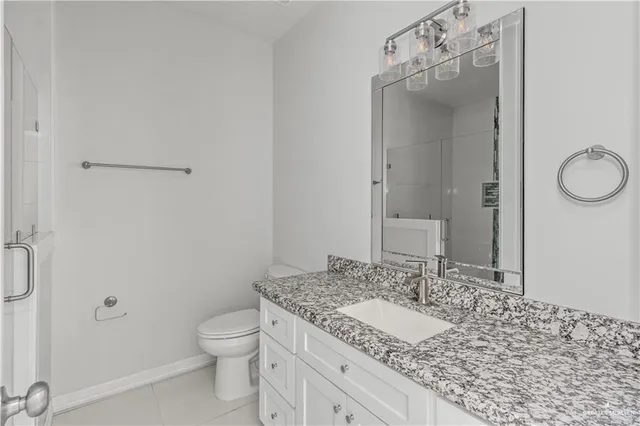 a bathroom with a granite countertop sink a toilet and a mirror