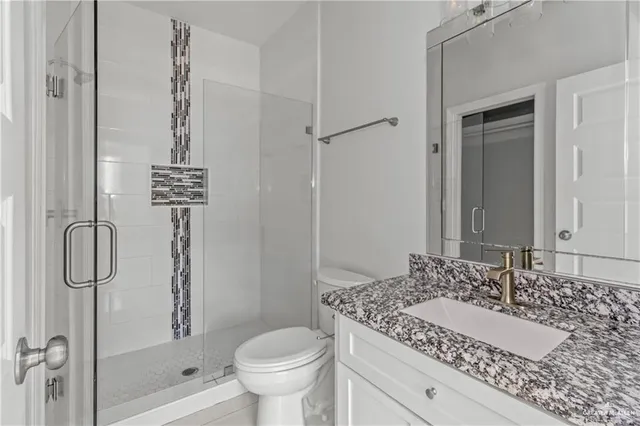 a bathroom with a granite countertop sink a toilet and shower