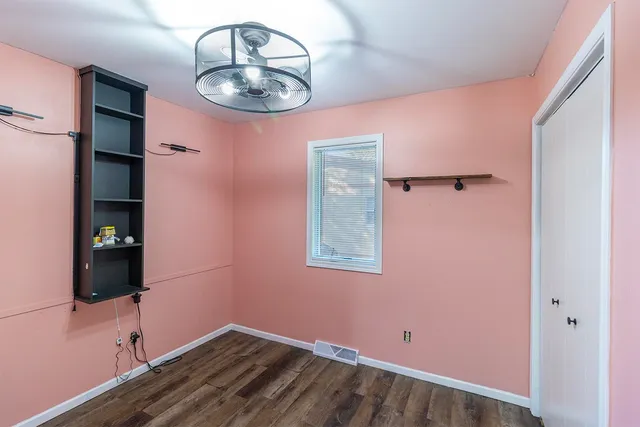 an empty room with wooden floor and mirror
