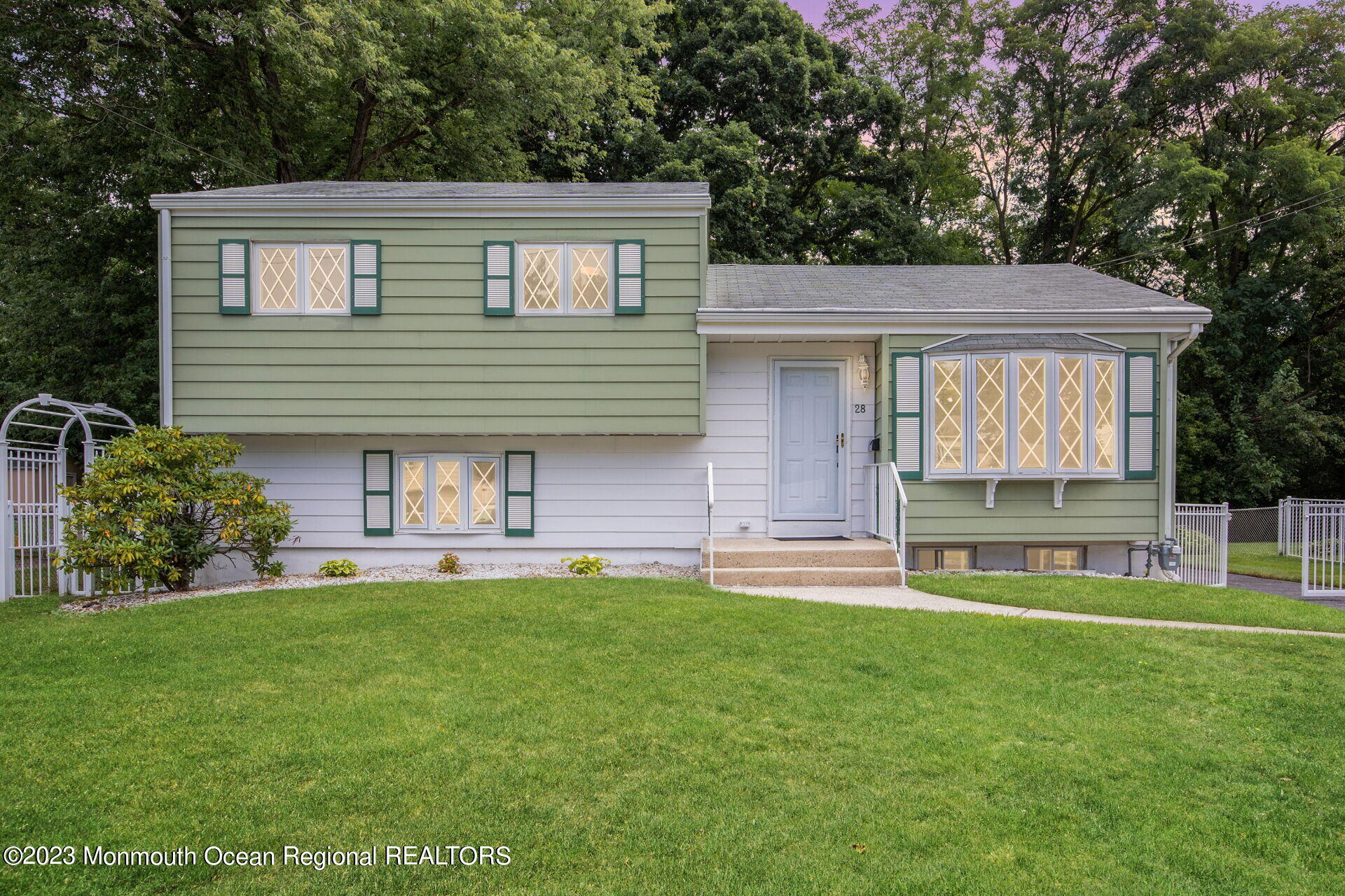 a front view of a house with a garden and trees