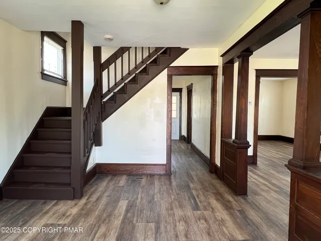 a view of a hallway with wooden floor and staircase