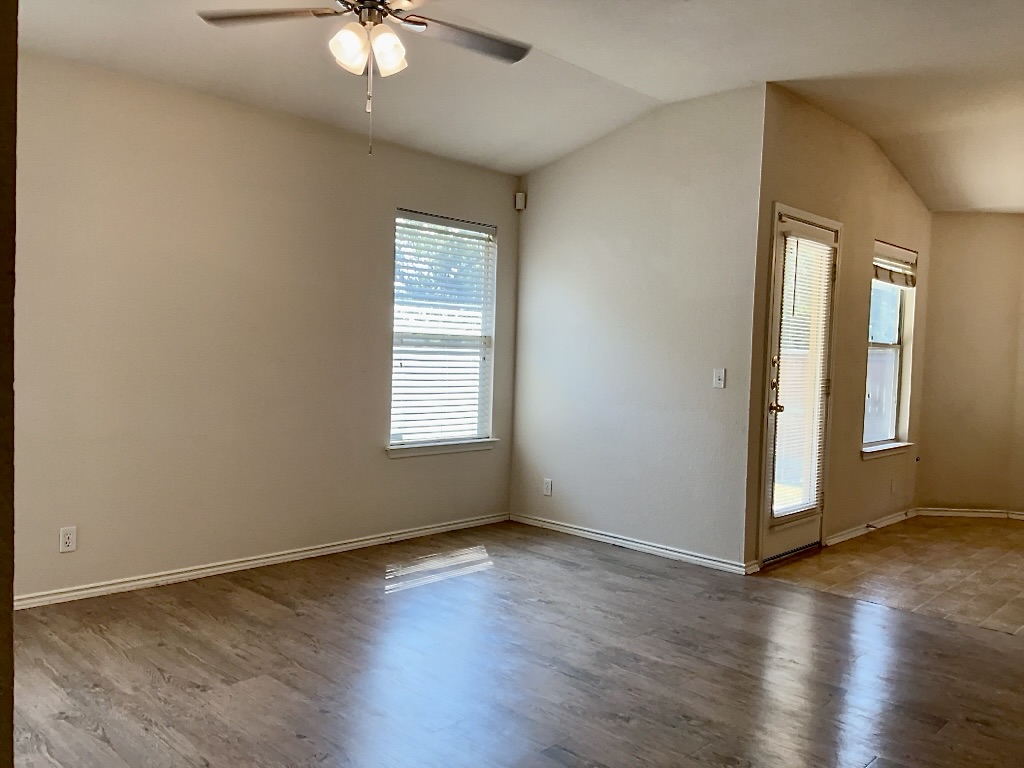 210 Delby Street Hutto, TX 78634 - Photo 4 of 15 an empty room with wooden floor and windows