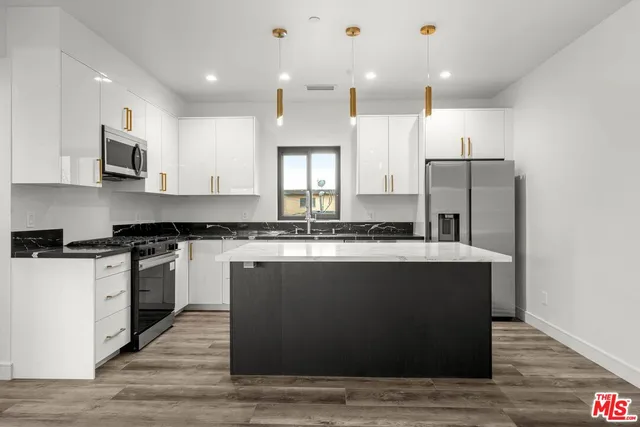 a kitchen with stainless steel appliances granite countertop a stove a sink and a refrigerator