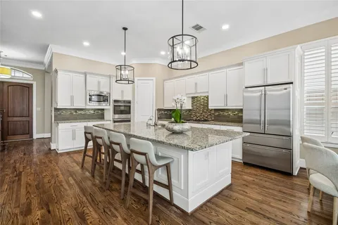 a kitchen with stainless steel appliances granite countertop a kitchen island hardwood floor and a sink