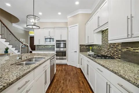 a kitchen with stainless steel appliances granite countertop a refrigerator a oven and a stove with wooden floor