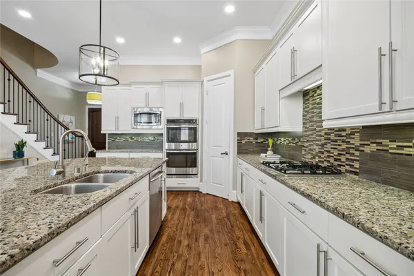 a kitchen with stainless steel appliances granite countertop a refrigerator a oven and a stove with wooden floor