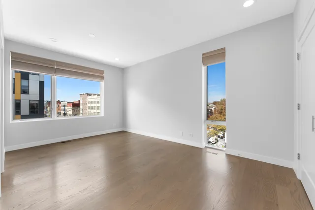 a view of a livingroom with wooden floor and a kitchen