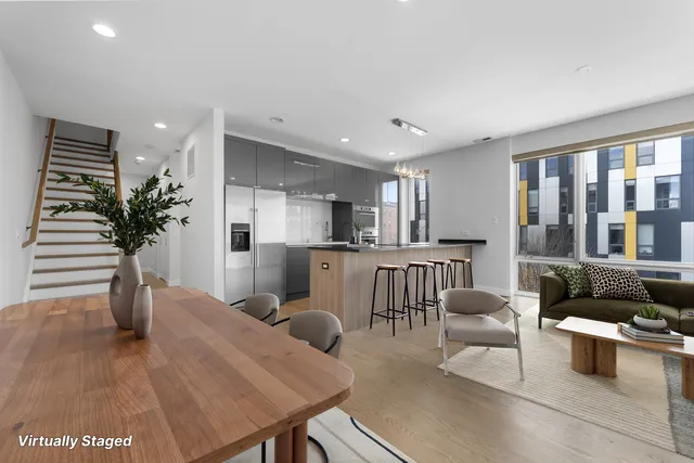 a living room with furniture potted plant and kitchen view