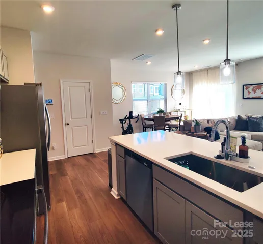 a kitchen with stainless steel appliances granite countertop a sink a counter space and a refrigerator