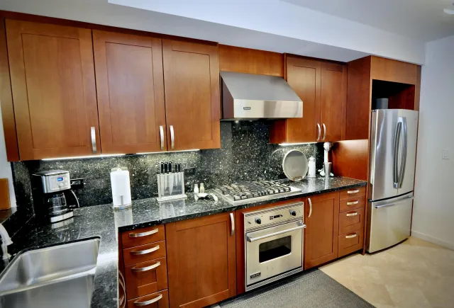 a kitchen with stainless steel appliances granite countertop a sink a stove and a refrigerator