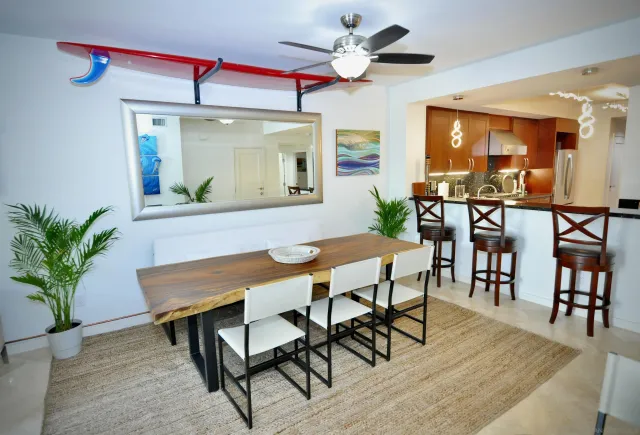 a view of a dining room and livingroom with furniture wooden floor a rug a painting and a chandelier