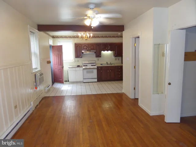 a large kitchen with stainless steel appliances a large counter top and wooden floors