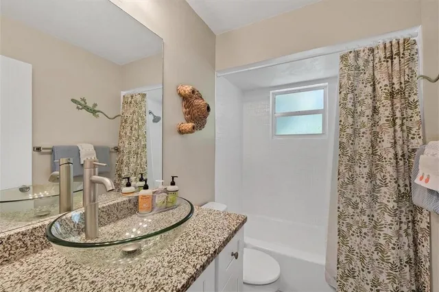 a bathroom with a granite countertop sink a toilet and a shower curtain