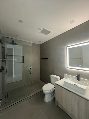 a bathroom with a granite countertop sink a toilet and shower