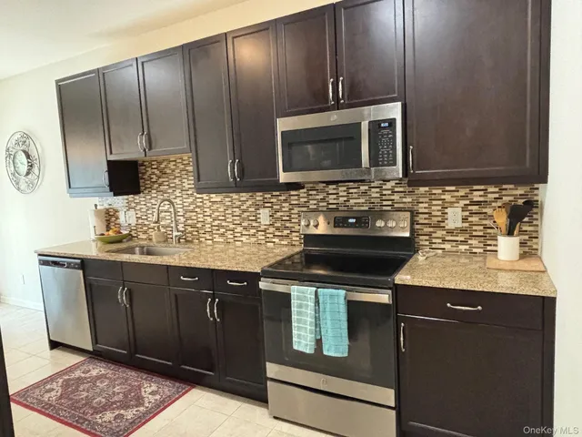 a kitchen with granite countertop stainless steel appliances wooden cabinets and a sink