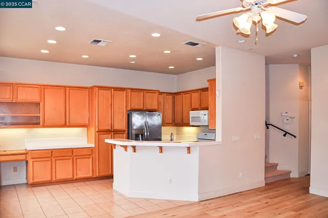 a view of a kitchen with kitchen island a sink wooden floor and stainless steel appliances