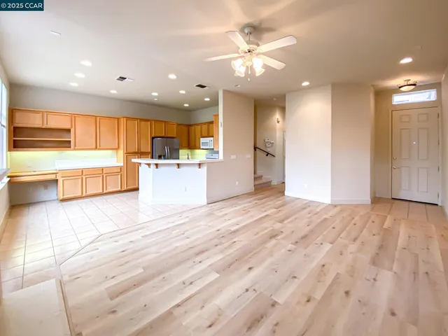 a view of a kitchen with kitchen island a sink wooden floor and a large window