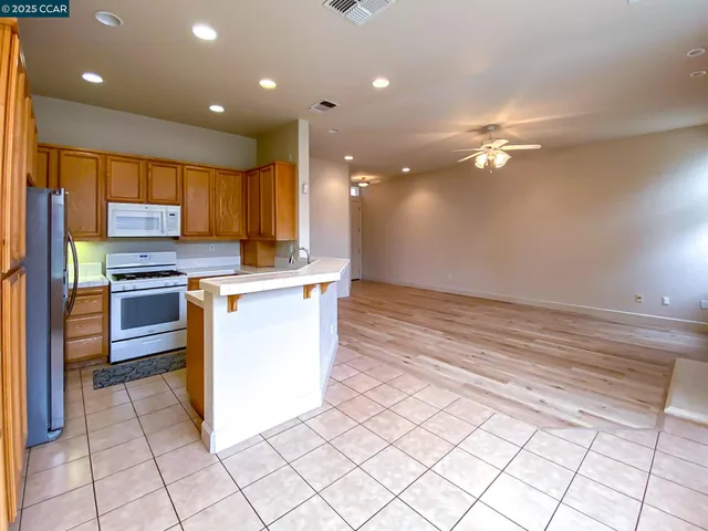 a kitchen with stainless steel appliances kitchen island granite countertop a refrigerator a stove and a sink