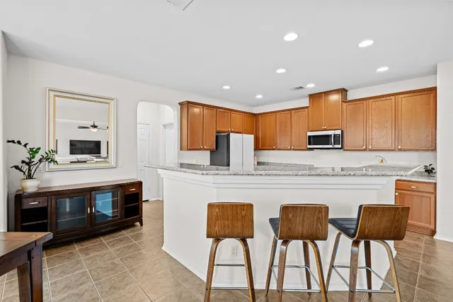 a kitchen with stainless steel appliances granite countertop a stove a sink a microwave a dining table and chairs