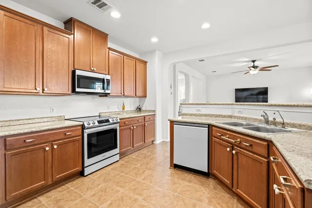 a kitchen with stainless steel appliances granite countertop a stove top oven a sink dishwasher and a microwave oven with cabinets