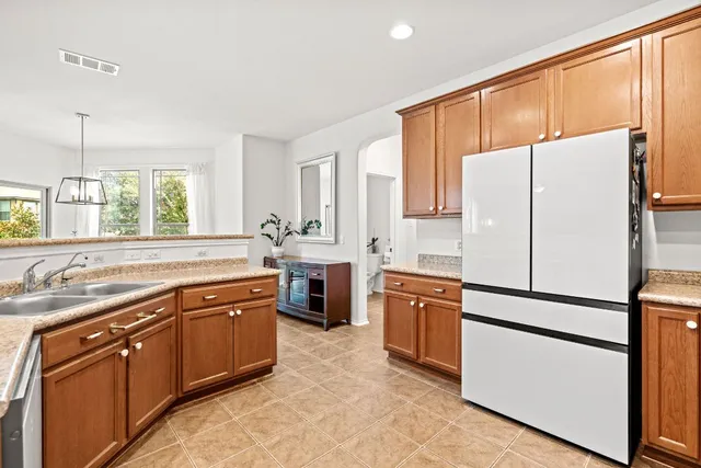 a kitchen with stainless steel appliances granite countertop a refrigerator stove a sink dishwasher and wooden cabinets