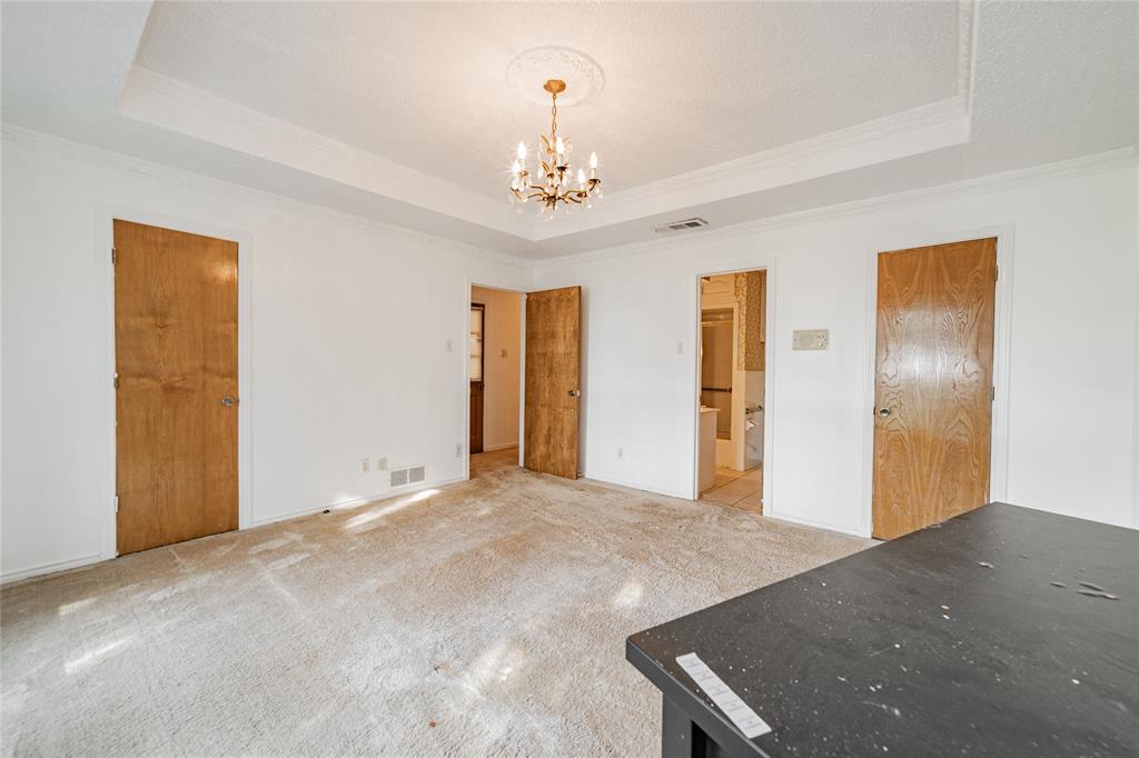4320 Hickox Road Rowlett, TX 75089 - Photo 27 of 37 Tray ceiling with decorative molding, chandelier lighting, white walls, and wood-panel doors