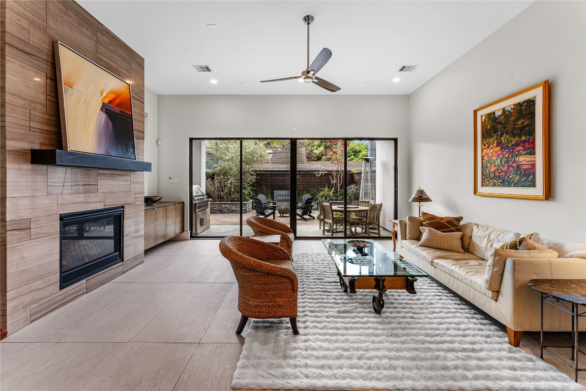 917 Peden Street Houston, TX 77006 - Photo 10 of 50 A sleek fireplace feature wall anchors the living space, offering warmth and contemporary style. Large glass doors open to the outdoor living area, creating a resort-style indoor-outdoor experience.